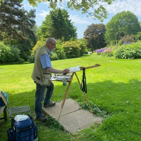 Artist standing behing easel painting the surrounding gardens.